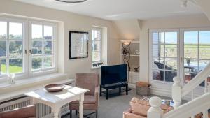 a living room with a table and chairs and windows at Heefwai in Morsum +3 photos