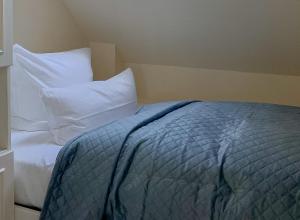 a bed with white pillows and a blue blanket at Heefwai in Morsum