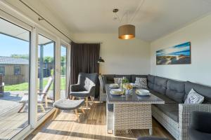 un soggiorno con un divano, un tavolo e delle sedie di Süsel Seeparx Ferienhaus Seezauber a Süsel