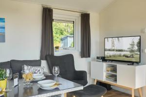 un soggiorno con un tavolo e una TV di Süsel Seeparx Ferienhaus Seezauber a Süsel