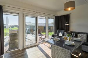 un soggiorno con tavolo, sedie e porte scorrevoli in vetro di Süsel Seeparx Ferienhaus Seezauber a Süsel Altre 15 foto