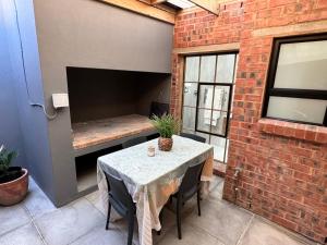 a patio with a table and a brick wall at CityScape Nest Suite Unit 2 in Mossel Bay
