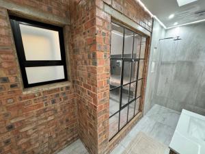 a bathroom with a brick wall and a window at CityScape Nest Suite Unit 2 in Mossel Bay +11 photos