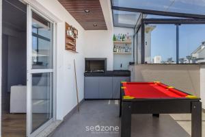 a ping pong table in a room with a kitchen at House with Jacuzzi, just 10min from the sea OSH in Florianópolis