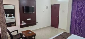 een slaapkamer met een bed, een tafel en een spiegel bij Hotel AMR Residency in Tiruchirappalli