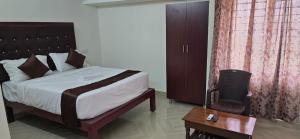 een slaapkamer met een bed, een tafel en een stoel bij Hotel AMR Residency in Tiruchirappalli
