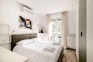 a white bedroom with a bed with towels on it at Pomodoro House - Luminoso appartamento vicino Linate, Duomo, Fabrique, Unipol Dome in Milan +39 photos