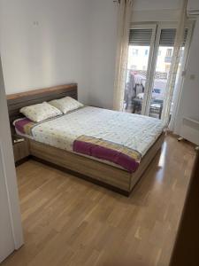 a bed in a bedroom with a wooden floor at Forte Mare Apartment in Podgorica