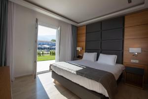 a bedroom with a large bed and a large window at Paleros Beach Resort in Paleros
