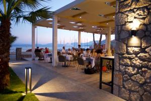 a group of people sitting at tables in a restaurant at Paleros Beach Resort in Paleros