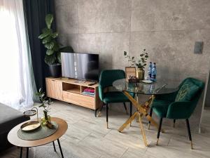 a living room with a glass table and green chairs at Przy Złotych Piaskach 1 in Sława