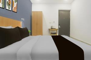 um quarto com uma cama grande e lençóis brancos e pretos em Hotel O Vivek inn Palace em Prayagraj