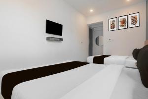 um quarto branco com 2 camas e uma televisão na parede em Hotel O Vivek inn Palace em Prayagraj