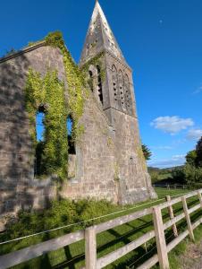 eine alte Kirche mit einem Zaun daneben in der Unterkunft The Widow's Cottage in Tipperary