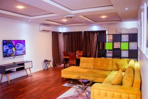 a living room with a yellow couch and a table at The Glass Residence Jabi in Abuja