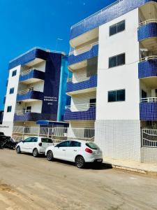 deux voitures blanches garées devant un bâtiment dans l'établissement Apartamento Premium Cama Queen Ar Cond centro cidade, à Formosa