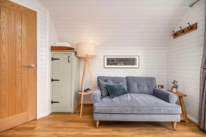 a living room with a blue couch and a door at Luxury Glamping Pods - The Heft & The Hirsel in Glasgow