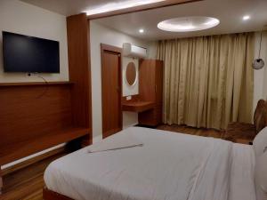 a hotel room with a bed and a flat screen tv at Palette Hotel and Resort Kankarbagh Main Road Formerly Aalcajars Inn in Bankipur