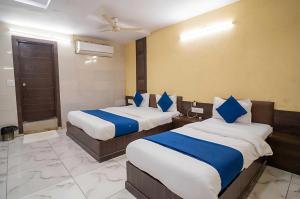 a bedroom with two beds with blue and white sheets at Hotel O Rajula Formerly The Urban Hotel in Rājula