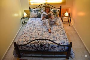 a woman sitting on a bed reading a book at A 2 pas de la plage, appartement cosy, confort, proche toutes commodités, Wifi haut débit, TV connectée, Netflix, climatiseur, Acte mariage pour couple national,3 nuits mimum in El Jadida