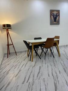 a table and chairs in a room with a painting at Maison Meublé de 3 CH Essos in Yaoundé