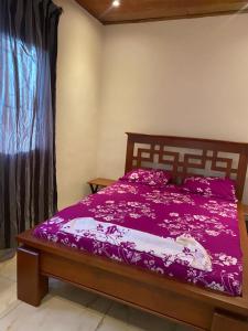 a bedroom with a bed with purple sheets and a window at Maison Meublé de 3 CH Essos in Yaoundé +3 photos