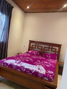 a bedroom with a bed with a purple bedspread at Maison Meublé de 3 CH Essos in Yaoundé