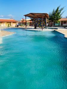 ein großer Pool mit blauem Wasser und einer Holzkonstruktion in der Unterkunft Pousada Licor de Caju in Barra Grande