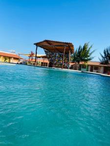 einen Pool mit einer Pergola und blauem Wasser in der Unterkunft Pousada Licor de Caju in Barra Grande