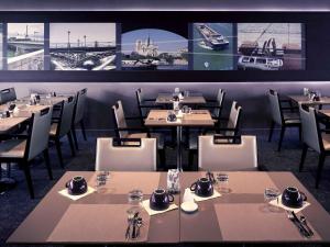 a restaurant with tables and chairs and pictures on the wall at Mercure Paris Ivry Quai De Seine in Ivry-sur-Seine
