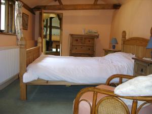 um quarto com uma cama grande e lençóis brancos em Granary Cottage em Hardwick