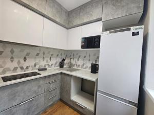 a kitchen with white cabinets and a refrigerator at Квартира in Zhezdi