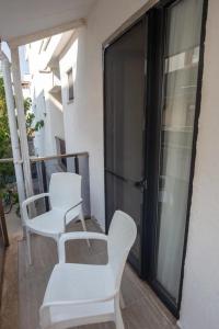 uma varanda com duas cadeiras brancas e uma porta em Cem Gül Hotel em Ayvalık
