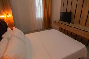 um quarto com uma cama branca e uma televisão em Cem Gül Hotel em Ayvalık