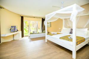 a bedroom with a white canopy bed and a television at Balafon Beach Resort in Kololi