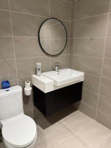 a bathroom with a sink and a toilet and a mirror at Quill Residence - Sky Glass Condo by Azmila in Kuala Lumpur