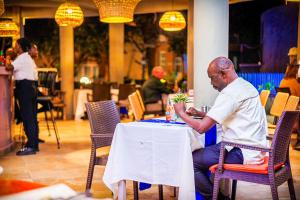 a man sitting at a table in a restaurant at Balafon Beach Resort in Kololi