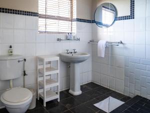 a white bathroom with a toilet and a sink at Harewood Lodge in East London