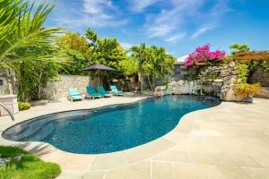 a swimming pool with two chairs and an umbrella at Kokomo Deluxe King - King Cottage in Turtle Cove