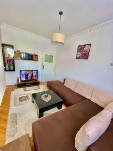 Una sala de estar con un sofá marrón y una mesa. en Comfy Downtown Apartment Prishtina, en Pristina