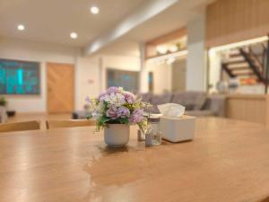a vase filled with flowers sitting on a table at Sawadee Guesthouse Suvarnabhumi in Lat Krabang