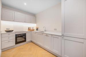 バースにあるStylish 3Bedroom Flat in Bath City Centerの白いキャビネット付きのウッドフロアの白いキッチン