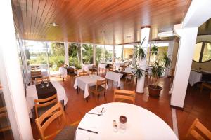 a restaurant with white tables and chairs and windows at Praia da Lota Beachfront Resort - Hotel & Apartments in Manta Rota