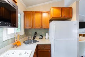 a kitchen with wooden cabinets and a white refrigerator at Kokomo Classic 2 Bedroom Couples Cottage in Turtle Cove