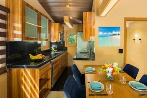 a kitchen with a wooden table and blue chairs at Kokomo Ultra-lux King - King Cottage in Turtle Cove +4 photos