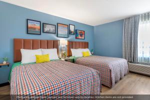 two beds in a room with blue walls and yellow pillows at Uptown Suites Extended Stay Nashville TN - Smyrna in Smyrna