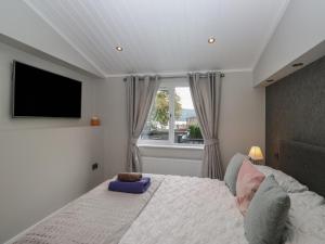 a bedroom with a bed and a tv and a window at 7 Lake View in Troutbeck Bridge