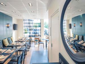 a dining room with tables and chairs and a mirror at Hôtel Mercure Thionville Centre Porte du Luxembourg in Thionville