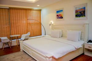 a bedroom with a white bed and a table and chairs at The Glass Residence Jabi in Abuja