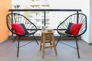 two black chairs with red pillows and a stool at Departamento a estrenar centro-sur Santa Fe - Urquiza II in Santa Fe